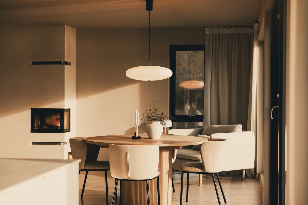 Dining table under a paper pendant lamp, with the fireplace lit behind it