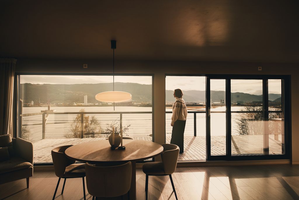 Round oak dining table with a wide view of the fjord