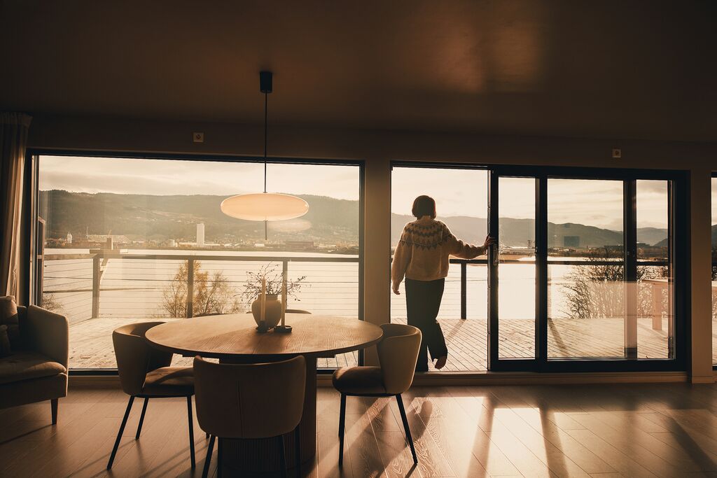 A guest at the open glass door of the dining room, looking out over the fjord