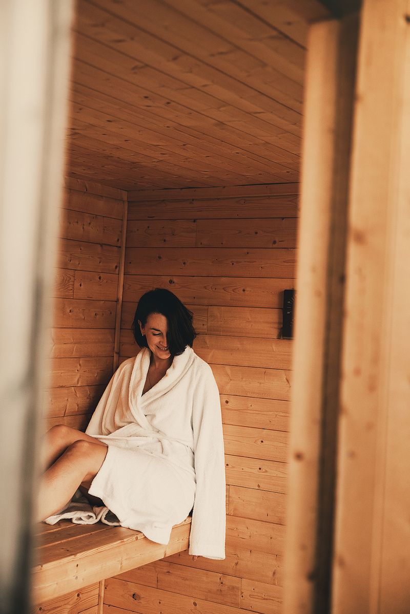 A guest in a white robe resting on the wooden sauna bench