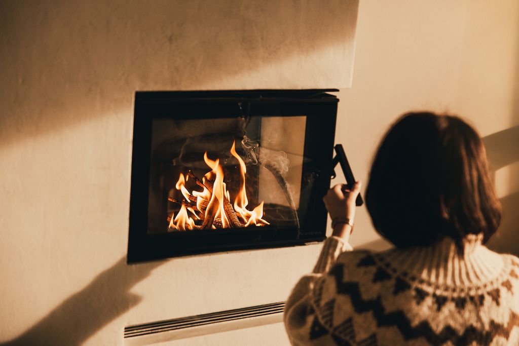 A guest in a Norwegian knit sweater lighting the fireplace
