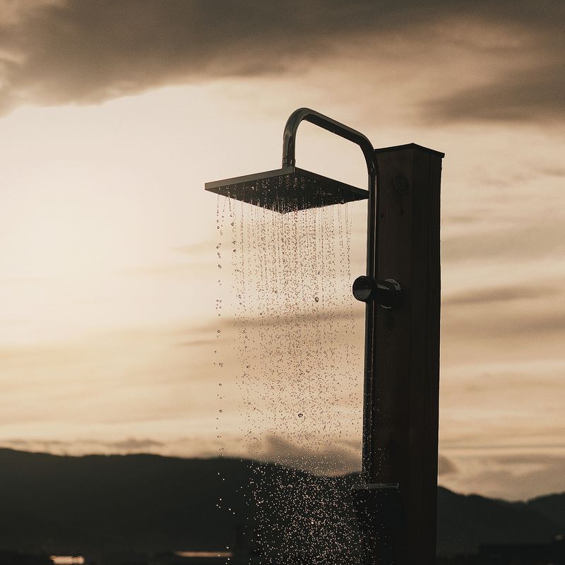 Water falling from the outdoor cold shower against the evening sky