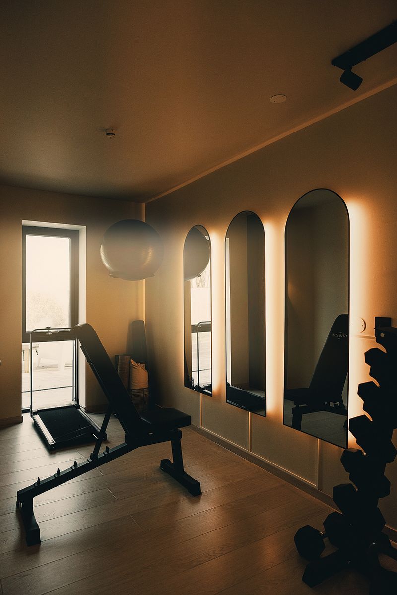 Private gym with arched mirrors, a bench, weights and an exercise ball