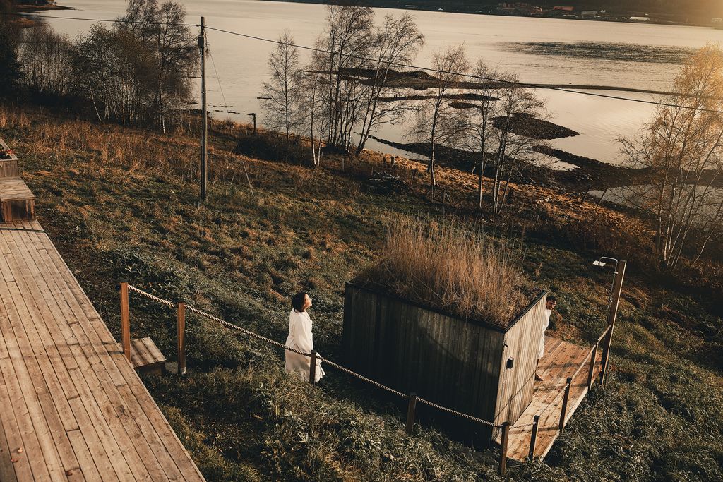 The sauna and outdoor shower on the grassy slope above the fjord shore