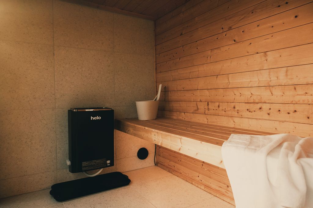 Inside the sauna: a wide pine bench, the heater and a white towel